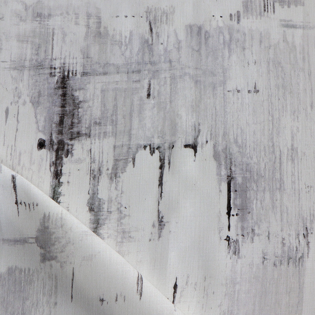 Detail of fabric in an abstract paint blot print in black and gray on a white field.