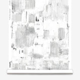 Partially unrolled wallpaper yardage in an abstract textural print in shades of gray on a white field.