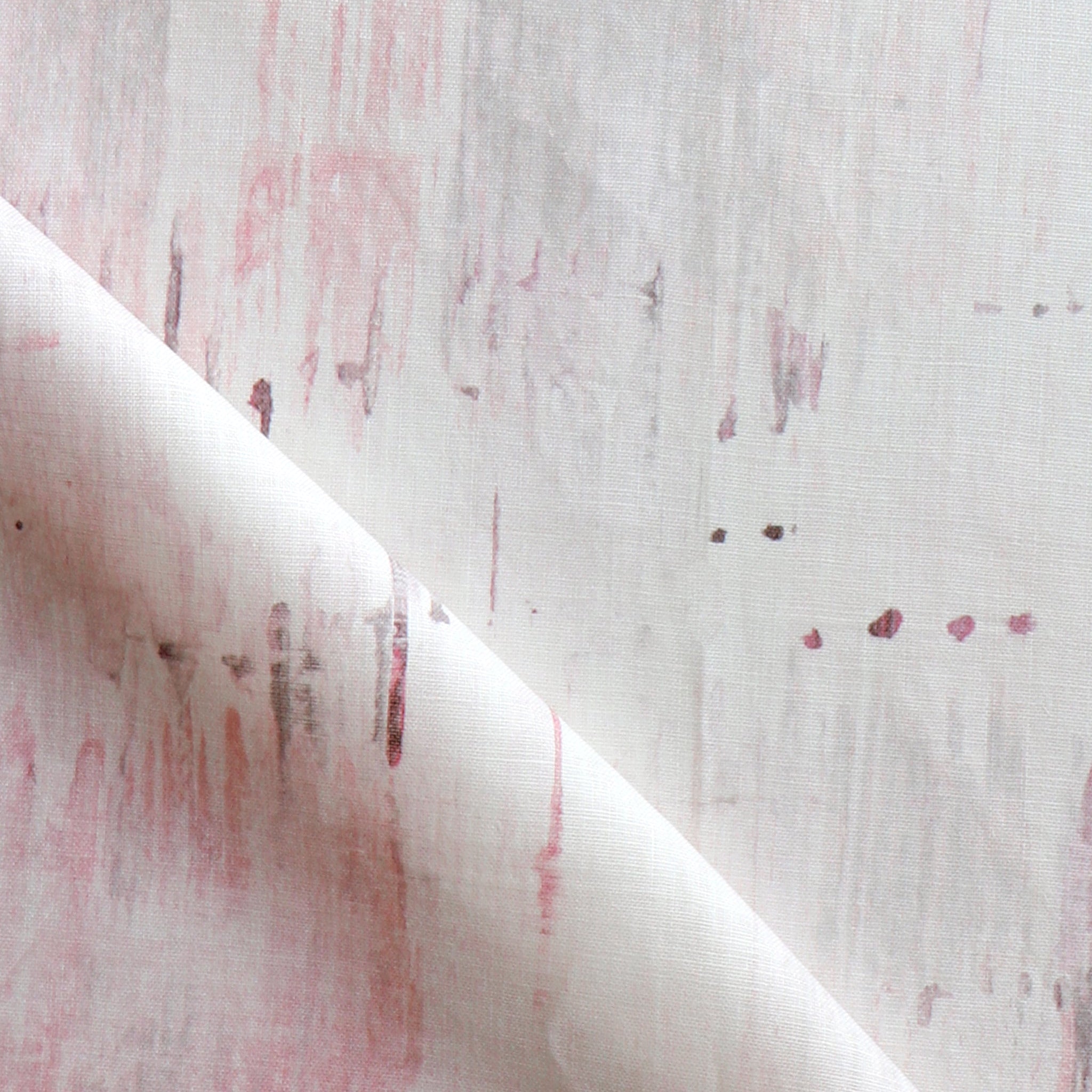 Detail of fabric in an abstract paint blot print in light pink on a white field.