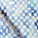 Detail of fabric in a painterly check pattern in shades of blue and navy on a white field.