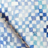 Detail of fabric in a painterly check pattern in shades of blue and navy on a white field.