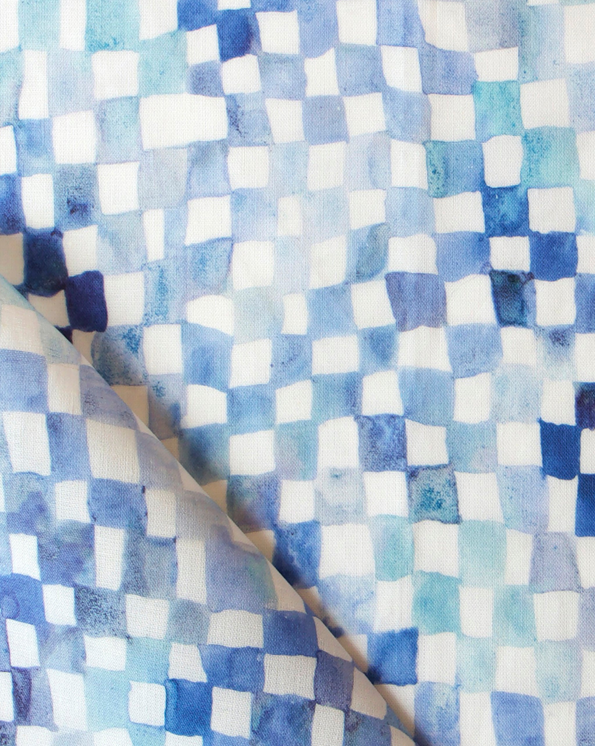 Detail of fabric in a painterly check pattern in shades of blue and navy on a white field.