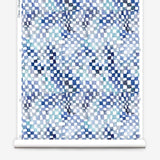 Partially unrolled wallpaper yardage in a painterly chess board print in shades of blue, navy and white.