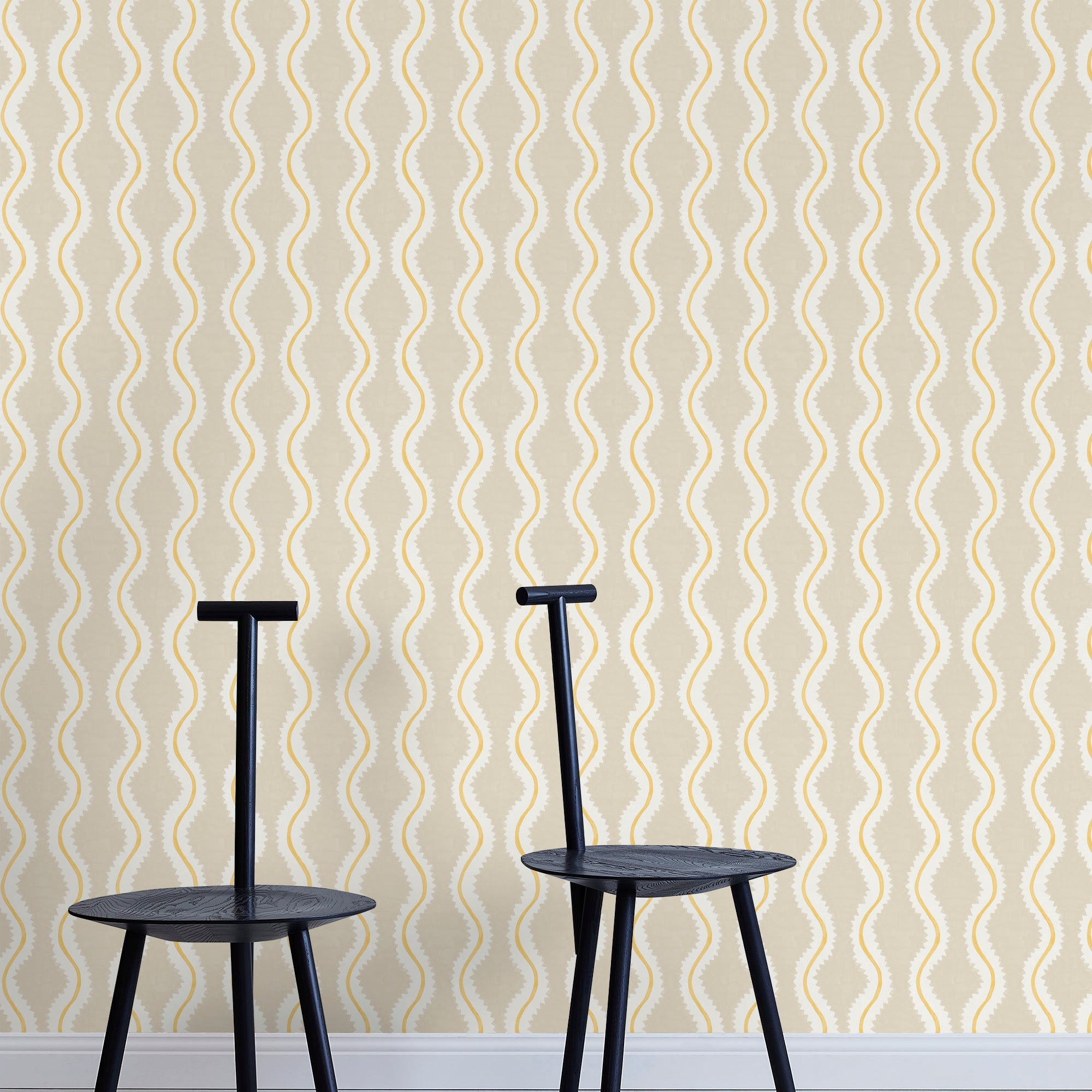 Two minimalist black chairs stand in front of a wall papered in a playful curvy stripe print in white, yellow and beige.