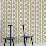 Two minimalist black chairs stand in front of a wall papered in a playful curvy stripe print in white, brown and olive.