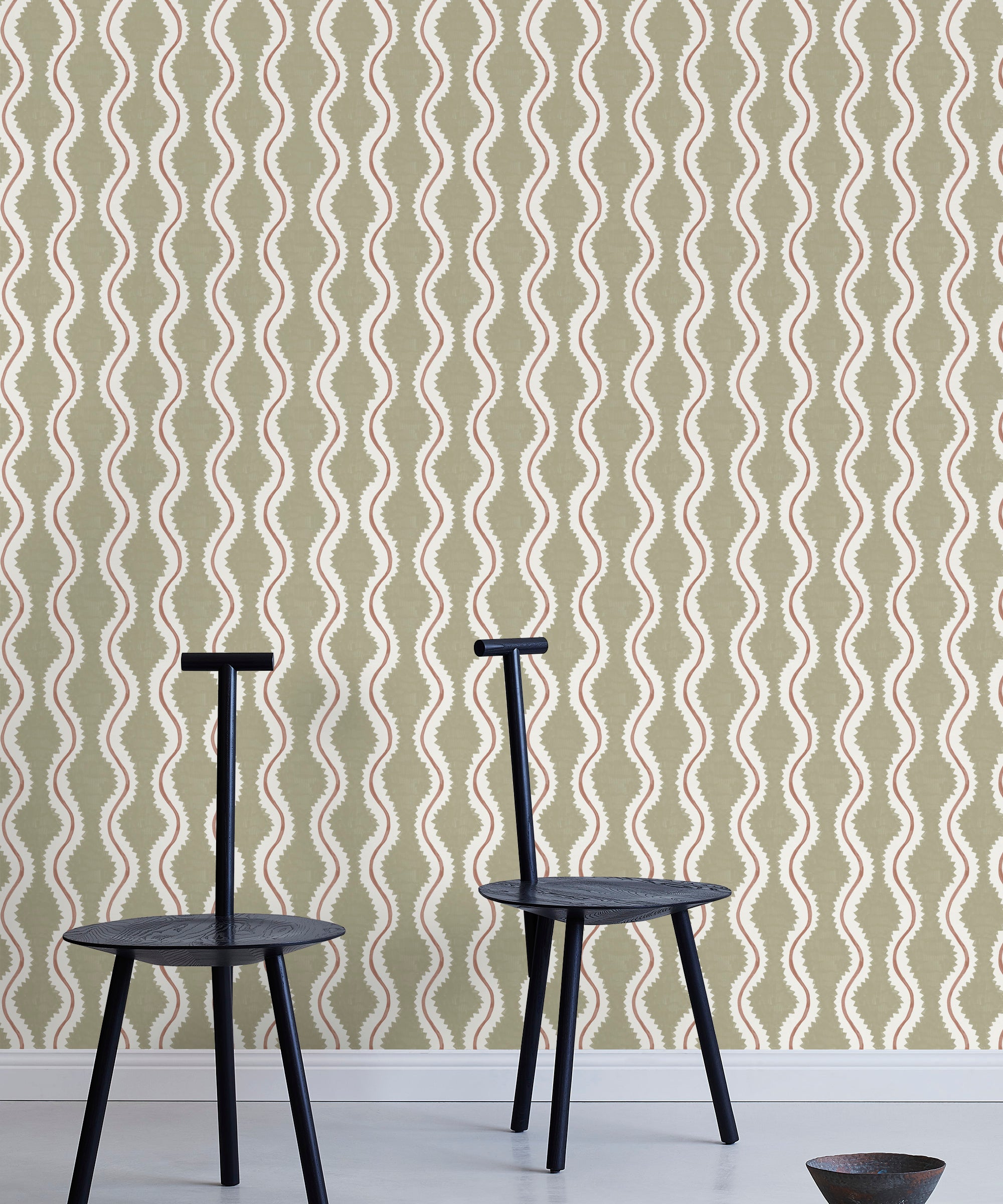 Two minimalist black chairs stand in front of a wall papered in a playful curvy stripe print in white, brown and olive.