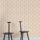 Two minimalist black chairs stand in front of a wall papered in a playful curvy stripe print in white, brown and light pink.