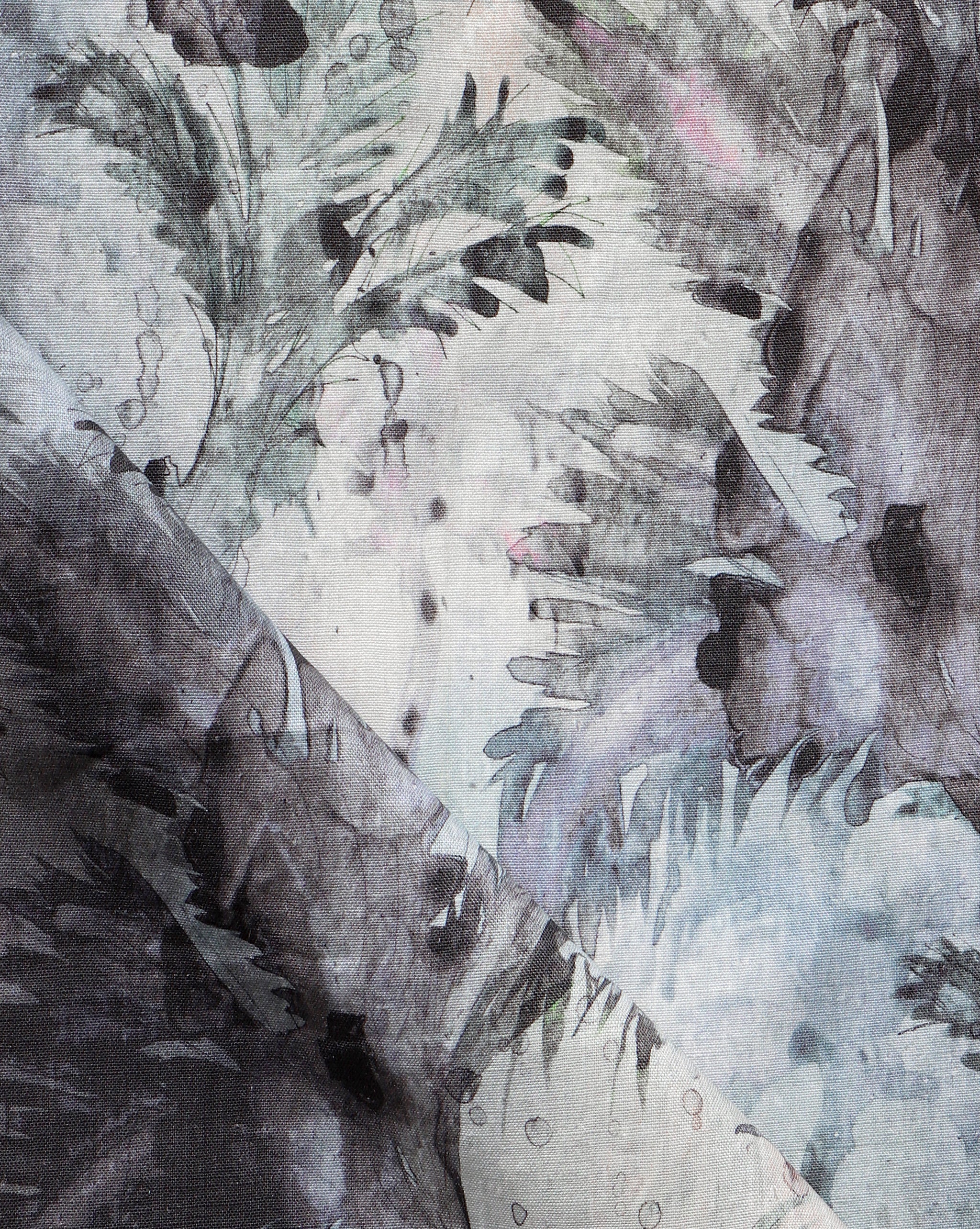 Detail of fabric in a painterly palm leaf print in shades of blue, pink and gray on a cream field.