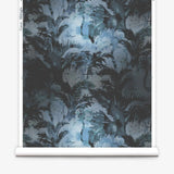 Partially unrolled wallpaper yardage in a painterly palm tree print in shades of gray and blue.