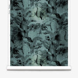 Partially unrolled wallpaper yardage in a painterly palm tree print in shades of gray and turquoise.