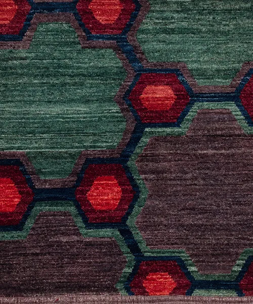 Close-up of a geometric patterned rug with red, green, and brown colors.