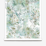 Partially unrolled wallpaper yardage in an abstract painted print in shades of green, tan and white.