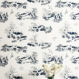 A vase of flowers stands in front of a wall covered in a playful illustrated car crash print in navy on a white field.