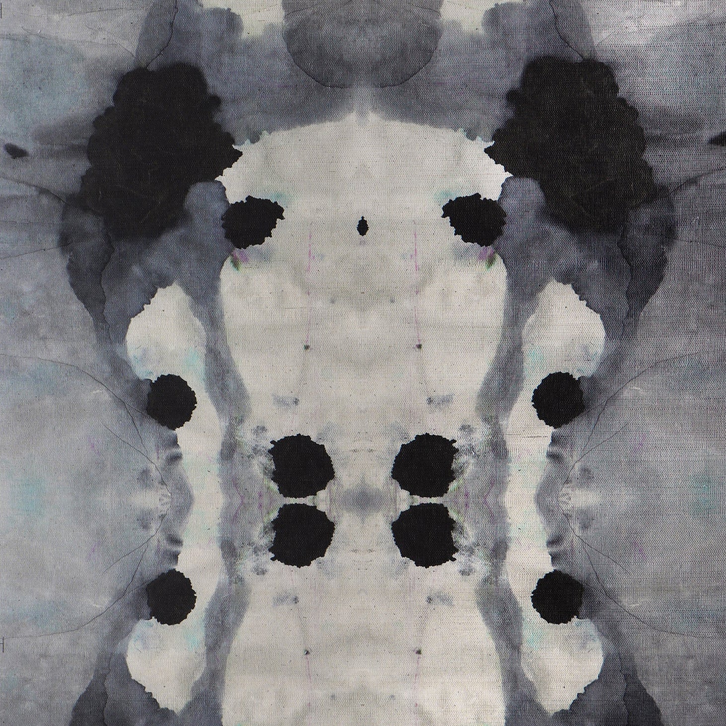 Close-up of wallpaper in an abstract ink blot print in shades of charcoal and gray on a tan field.