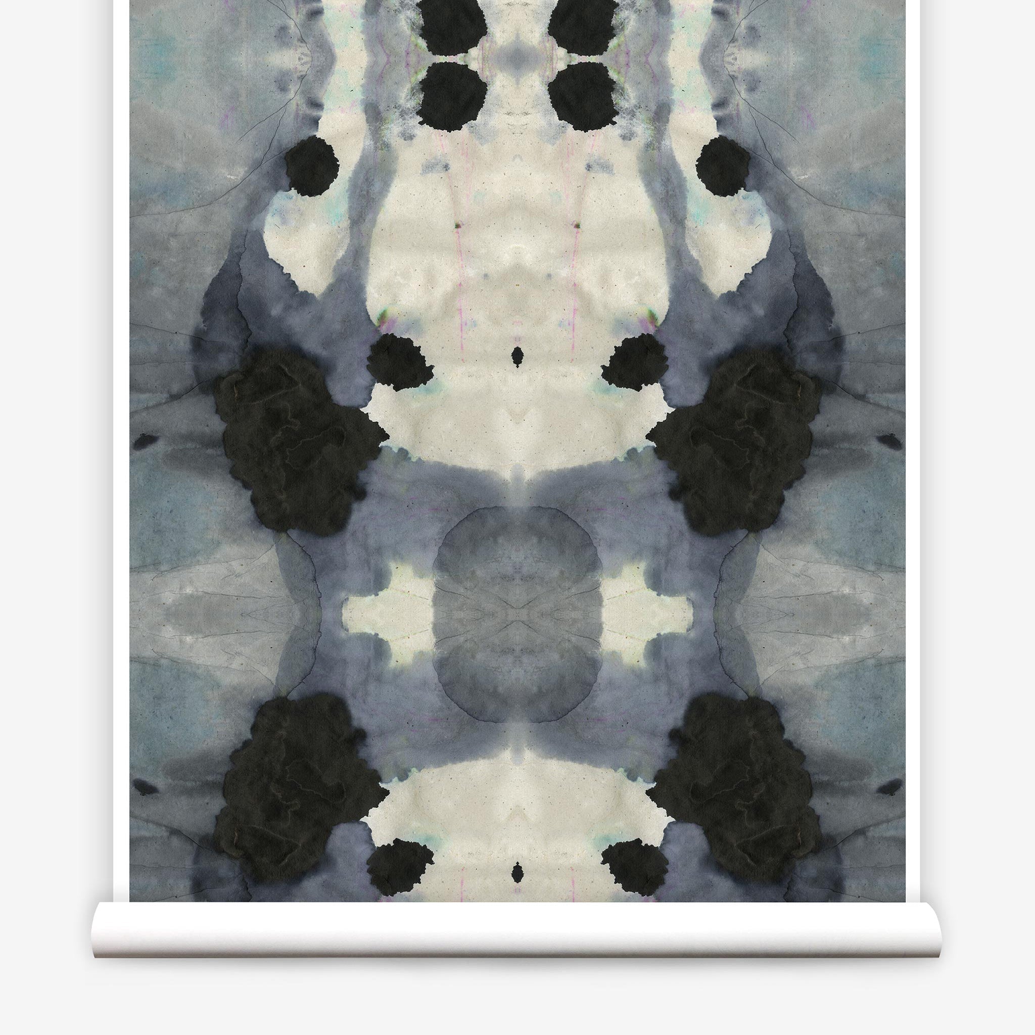 Partially unrolled wallpaper yardage in an abstract ink blot print in charcoal, gray and tan.