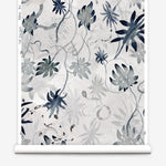Partially unrolled wallpaper yardage in a playful leaf and snake print in gray and navy on a cream field.