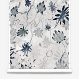 Partially unrolled wallpaper yardage in a playful leaf and snake print in gray and navy on a cream field.