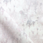 Detail of fabric in a painterly tree print in light pink and purple on a cream field.