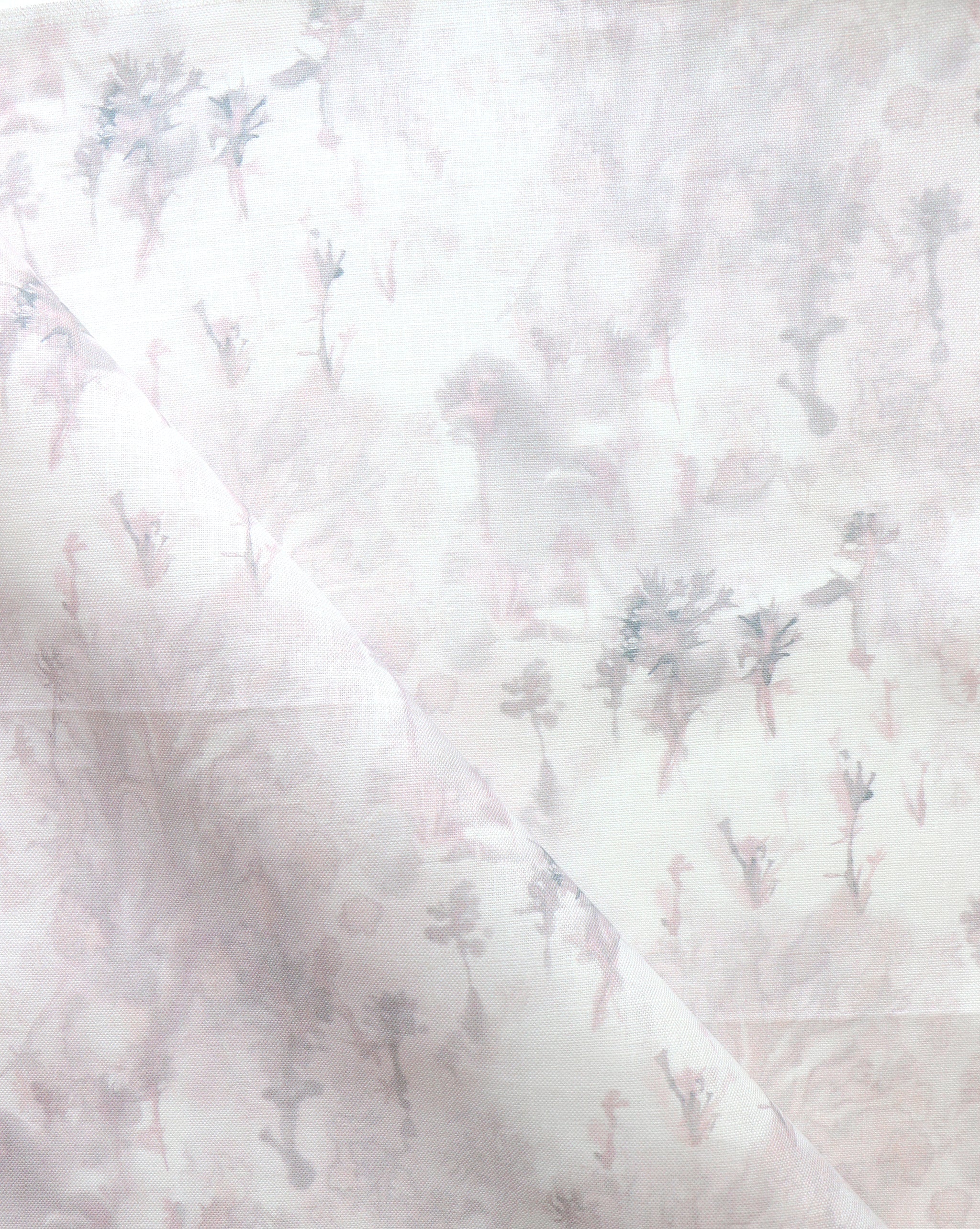 Detail of fabric in a painterly tree print in light pink and purple on a cream field.