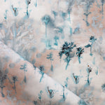 Detail of fabric in a painterly tree print in light turquoise and gray on a coral field.