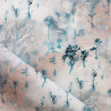 Detail of fabric in a painterly tree print in light turquoise and gray on a coral field.