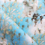 Detail of fabric in a painterly tree print in gray and tan on a turquoise field.