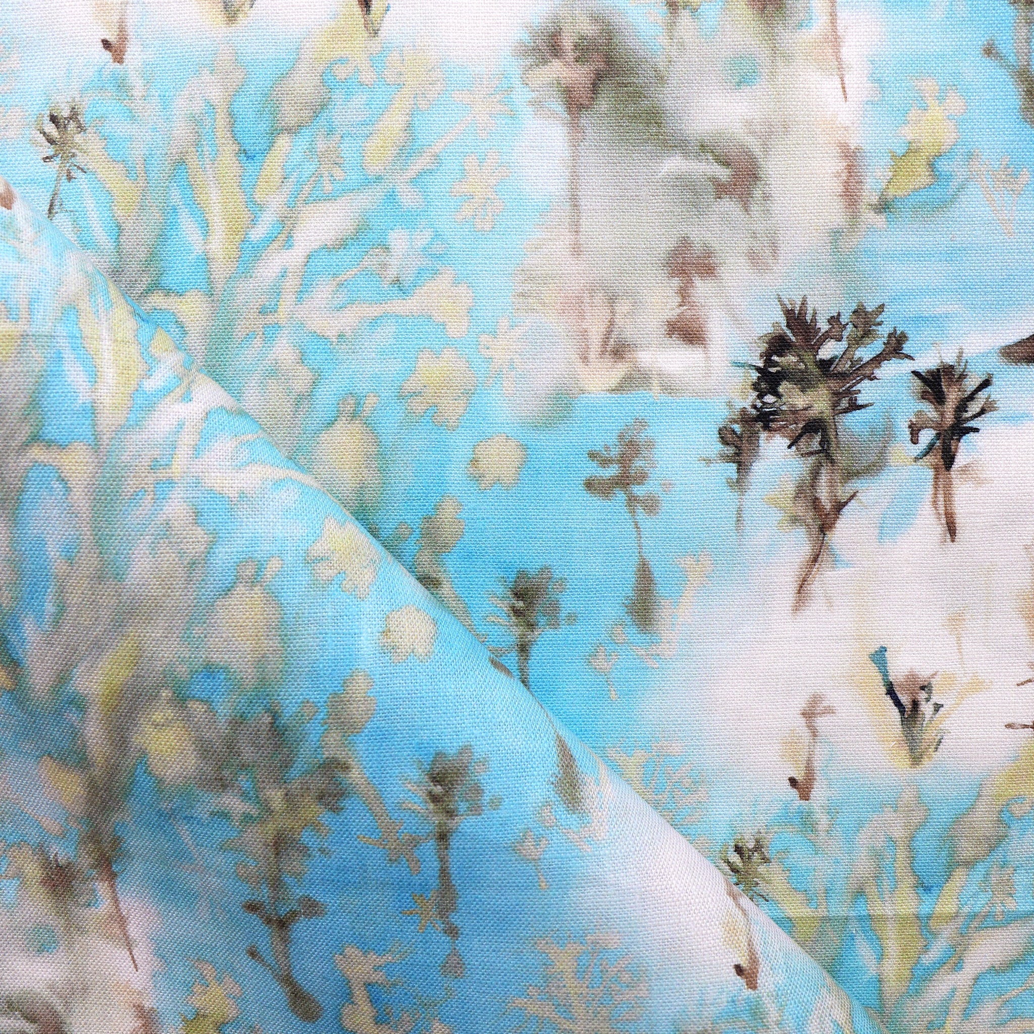 Detail of fabric in a painterly tree print in gray and tan on a turquoise field.