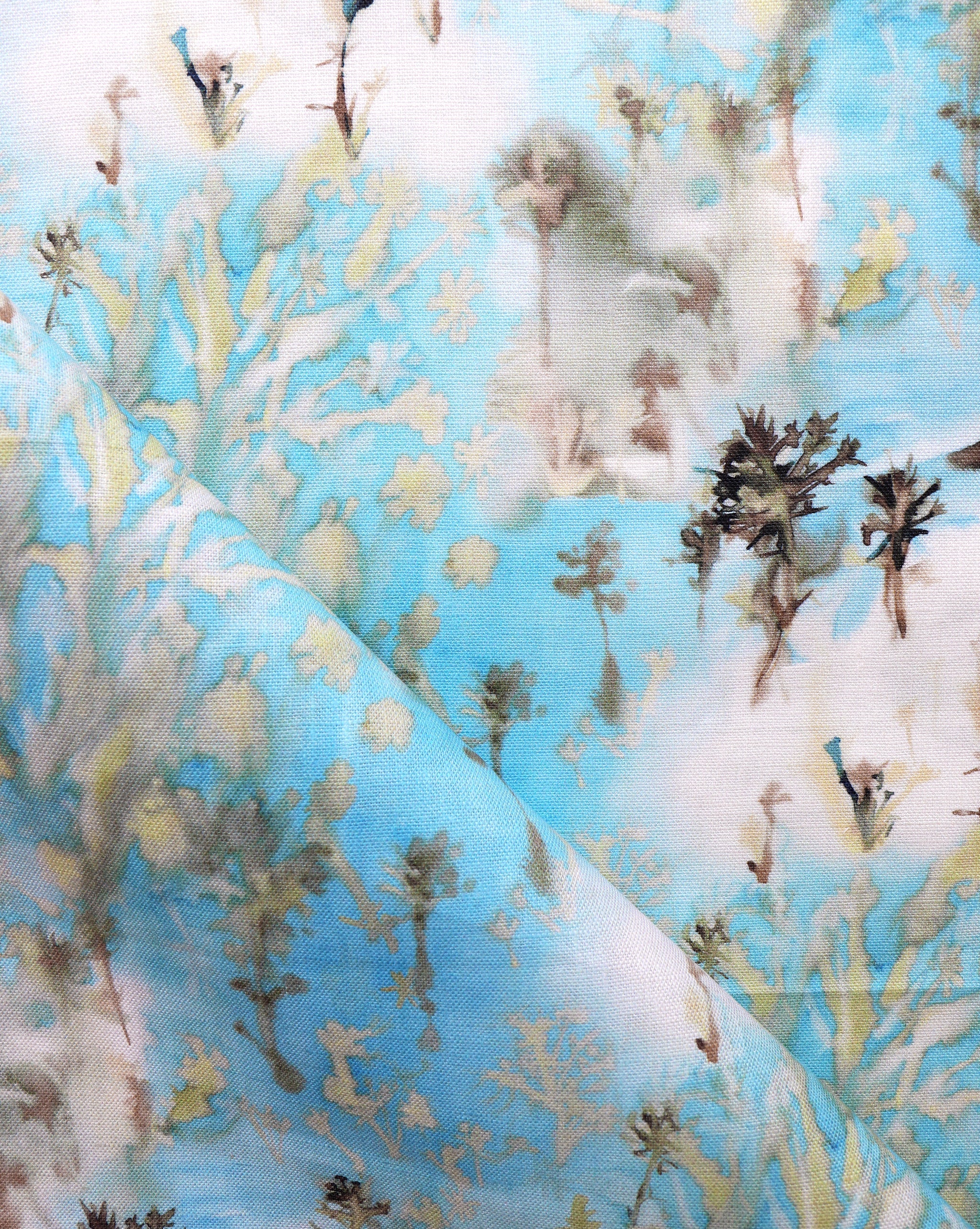 Detail of fabric in a painterly tree print in gray and tan on a turquoise field.