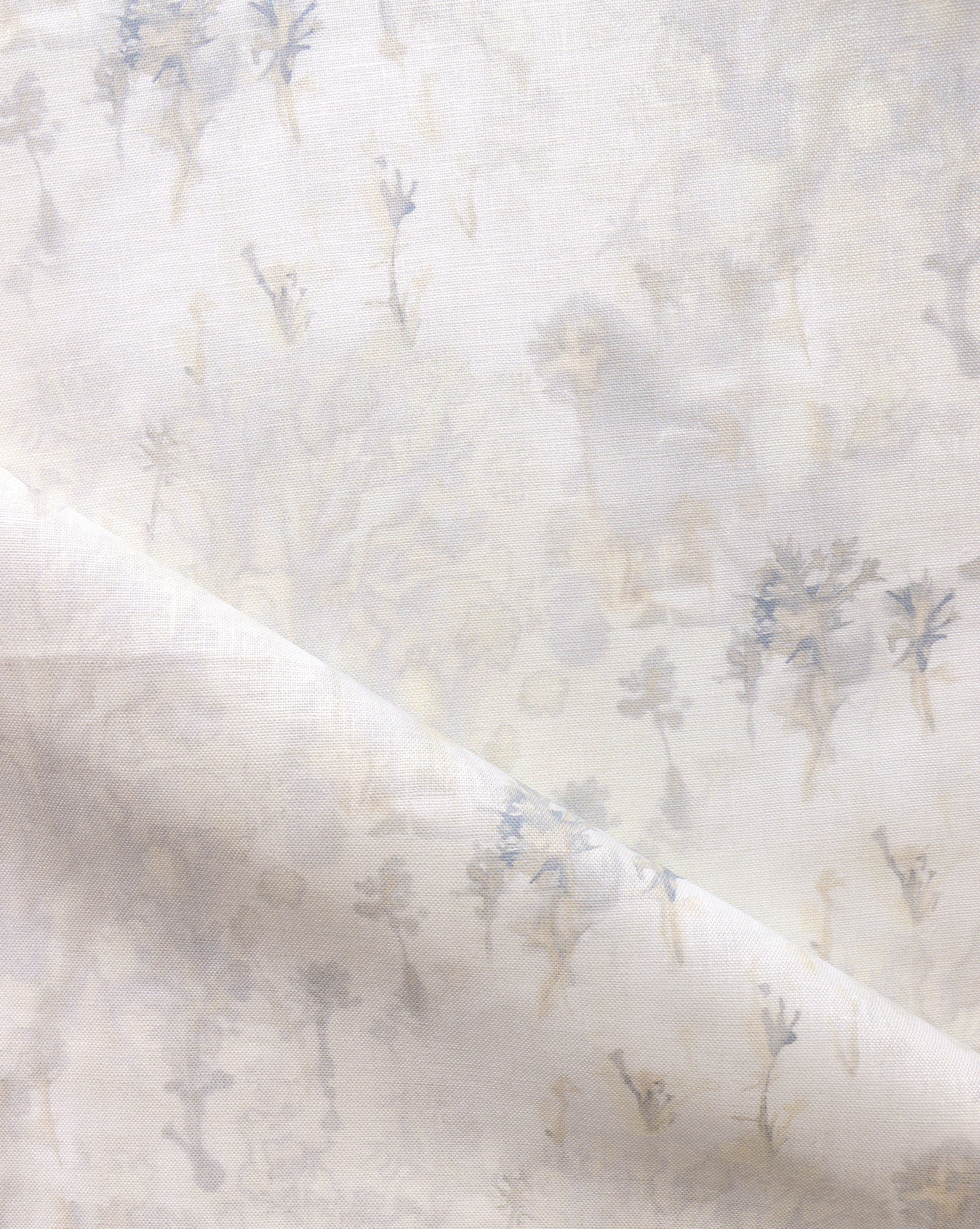 Detail of fabric in a painterly tree print in gray and tan on a white field.