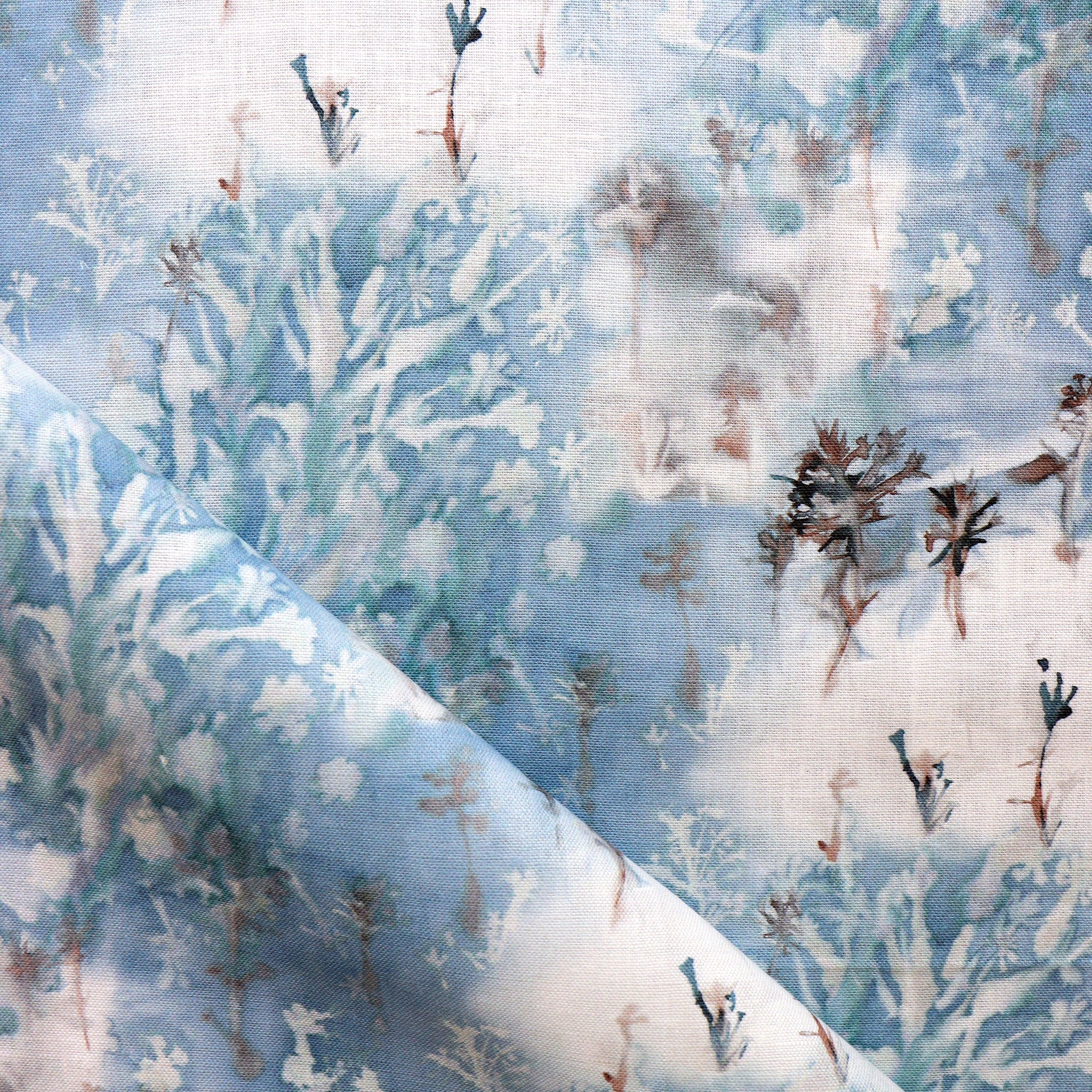 Detail of fabric in a painterly tree print in blue, gray and tan on a white field.