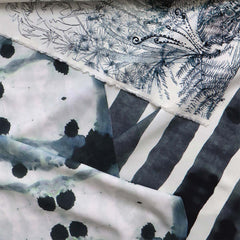 Overlapping swatches of printed silk fabric in navy on white backgrounds: a stripe, an inkblot print and a floral print.