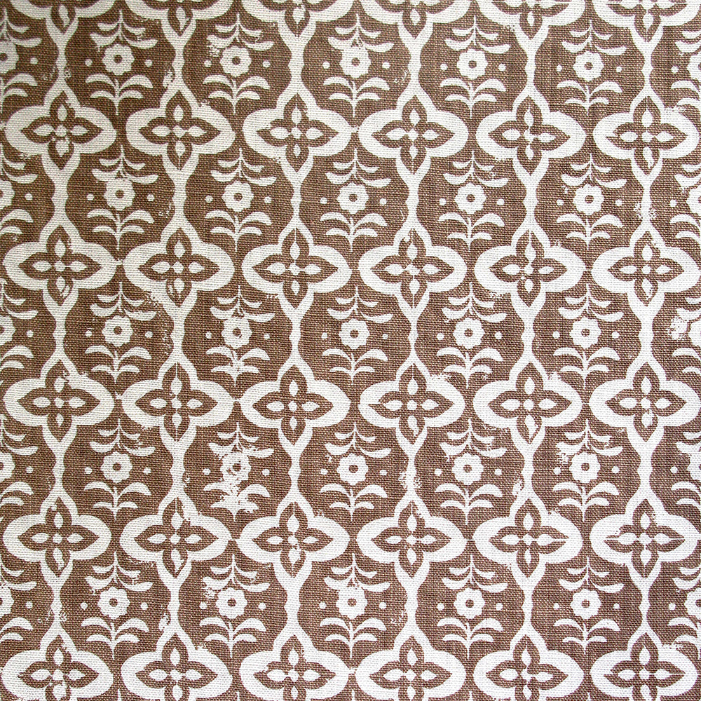 Detail of fabric in a floral grid print in cream on a light brown field.