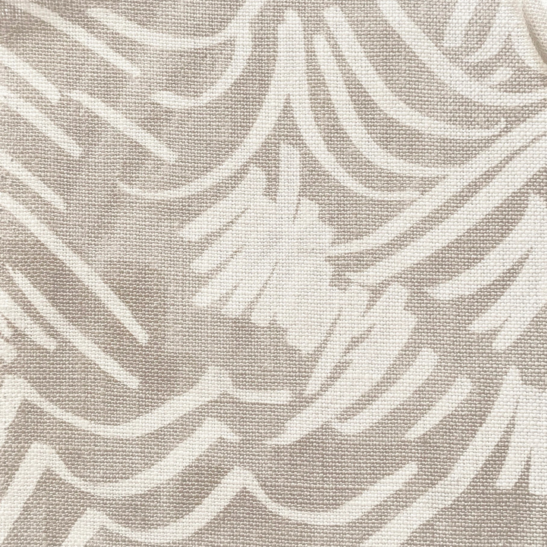 Close-up of fabric in a painterly wave print in white on a cream field.