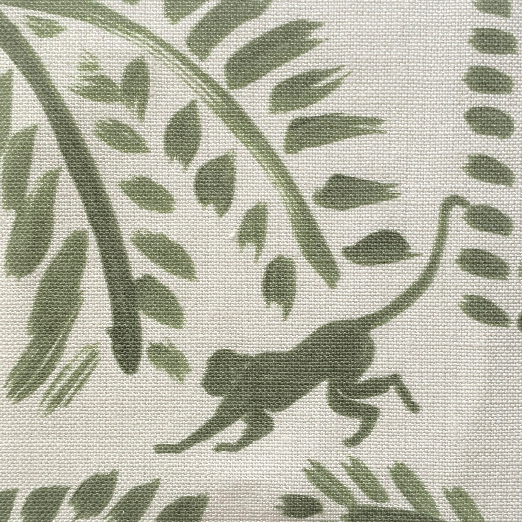 Close-up of fabric in a playful palm tree and monkey print in green on a cream field.