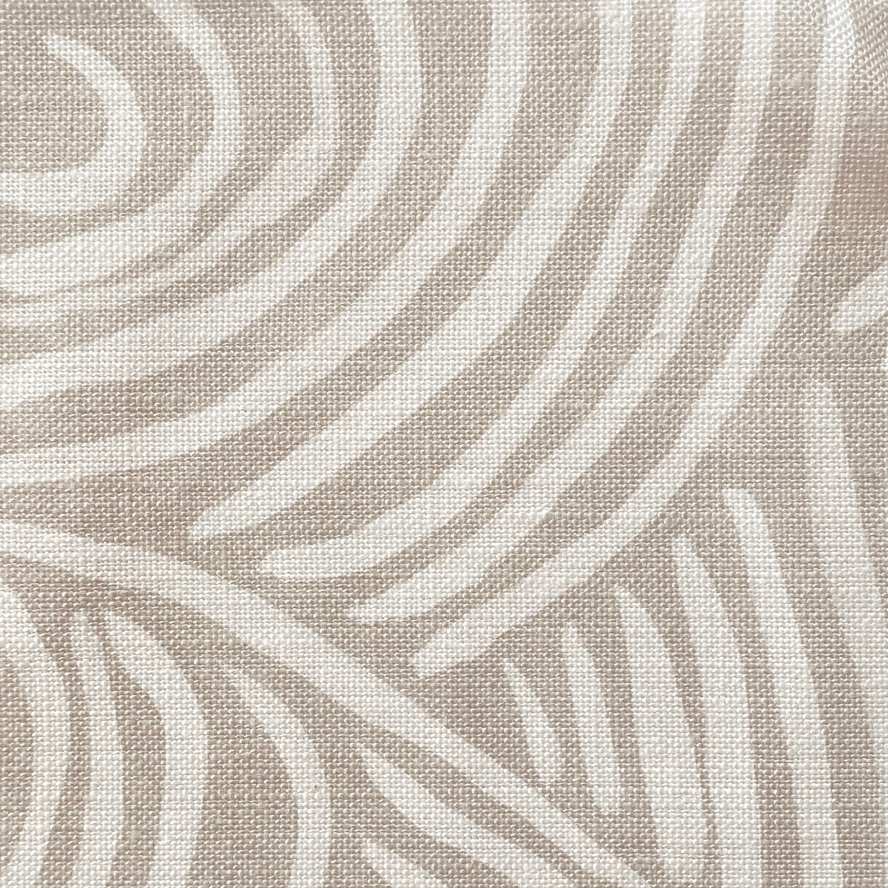 Close-up of fabric in an abstract linear print in white on a cream field.