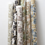 A group of fabric rolls leaned against a wall, all in different colorways of the same painterly palm tree print.