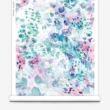 Partially unrolled wallpaper yardage in an abstract paint blotch print in pink, green, turquoise and white.
