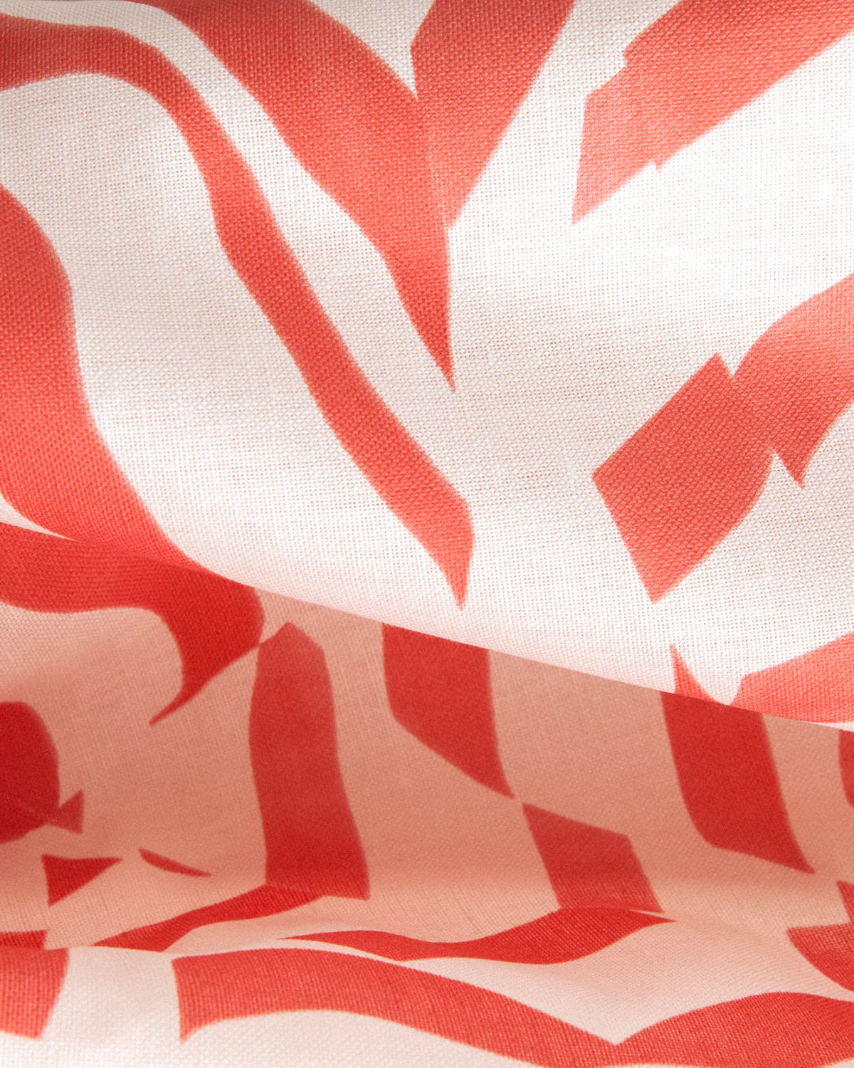 Draped fabric yardage in a playful broken stripe print in coral on a cream field.