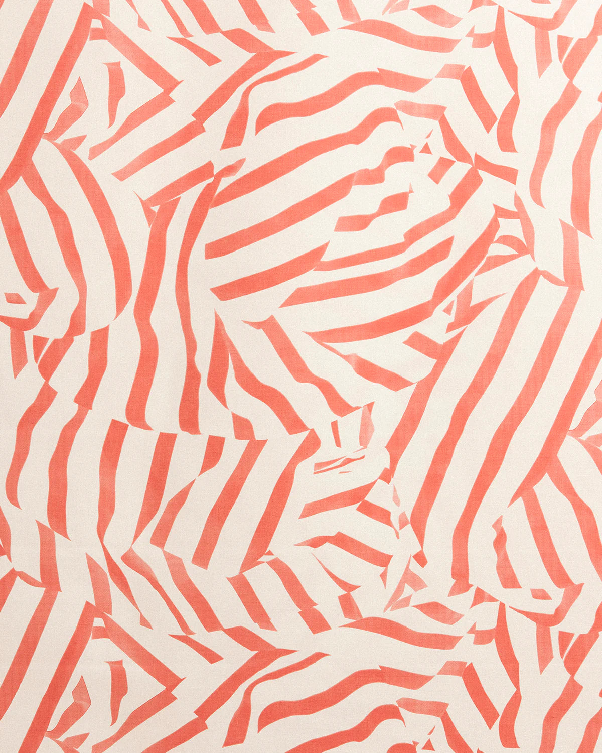 Detail of fabric in a playful broken stripe print in coral on a cream field.