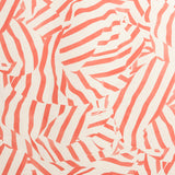 Detail of fabric in a playful broken stripe print in coral on a cream field.