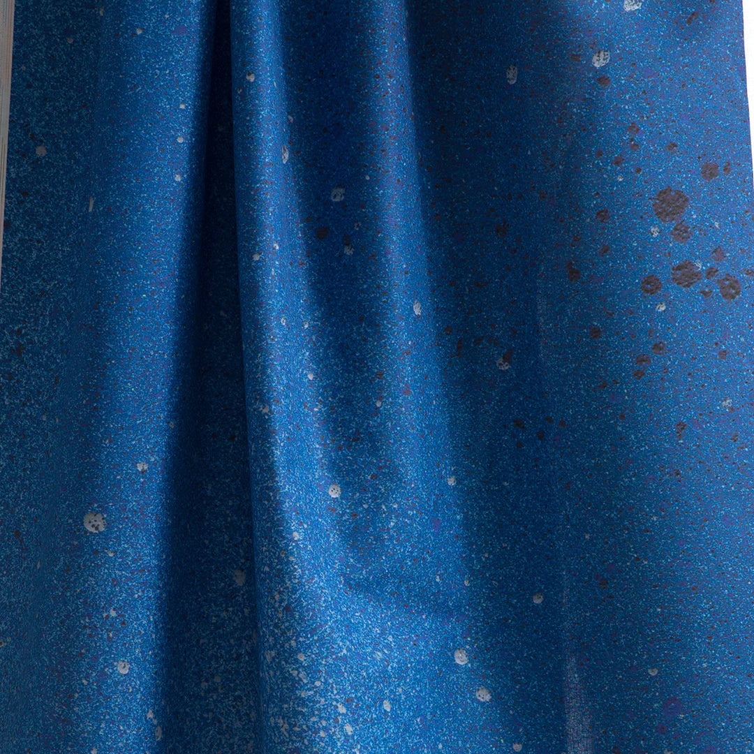 Draped fabric yardage in an abstract ombré paint splatter print in shades of blue and gray.