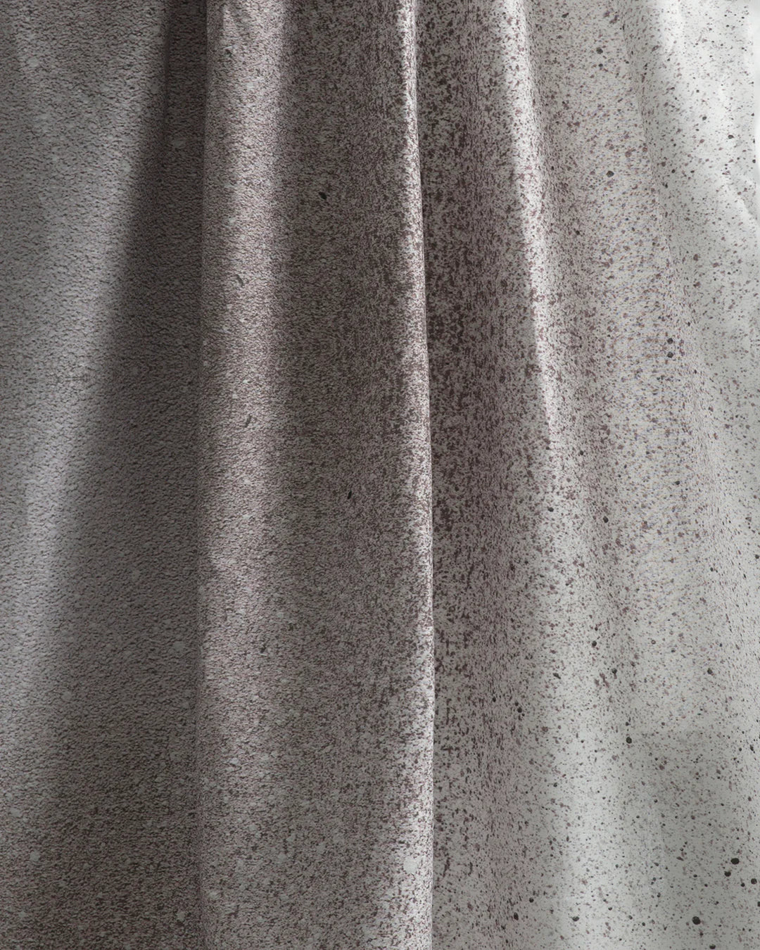 Draped fabric yardage in an abstract ombré paint splatter print in shades of gray and white.