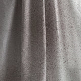 Draped fabric yardage in an abstract ombré paint splatter print in shades of gray and white.