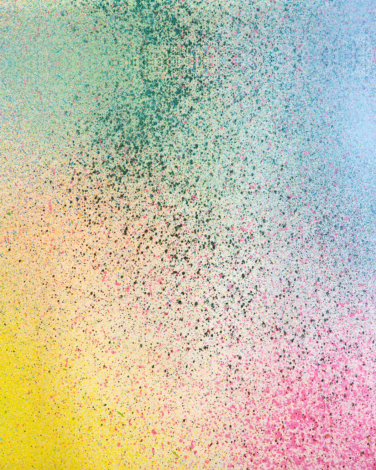 Detail of fabric in an abstract ombré paint splatter print in shades of yellow, pink, green and blue.