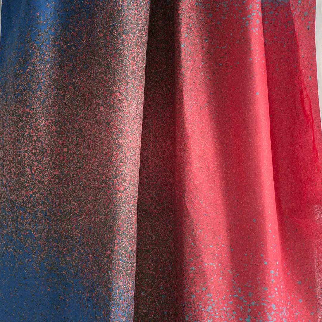 Draped fabric yardage in an abstract ombré paint splatter print in shades of blue, red and navy.