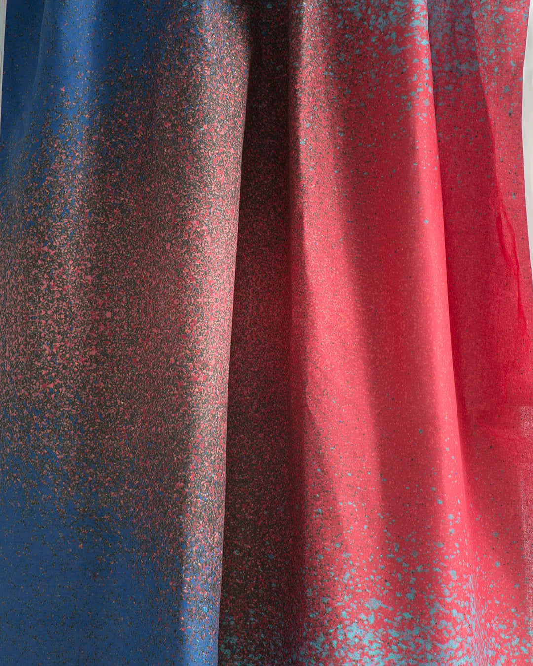 Draped fabric yardage in an abstract ombré paint splatter print in shades of blue, red and navy.