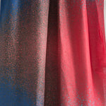 Draped fabric yardage in an abstract ombré paint splatter print in shades of blue, red and navy.