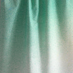 Draped fabric yardage in an abstract ombré paint splatter print in shades of turquoise, green and white.