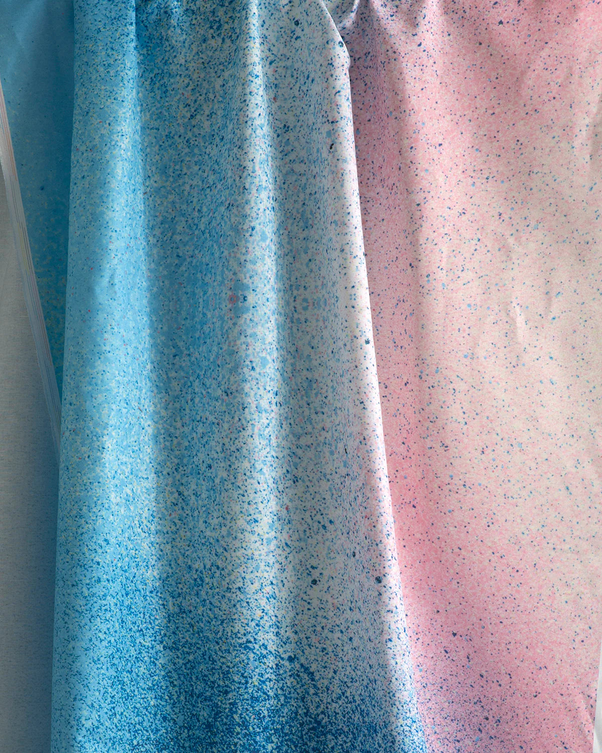 Draped fabric yardage in an abstract ombré paint splatter print in shades of blue, white, pink and navy.