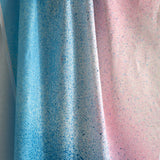 Draped fabric yardage in an abstract ombré paint splatter print in shades of blue, white, pink and navy.